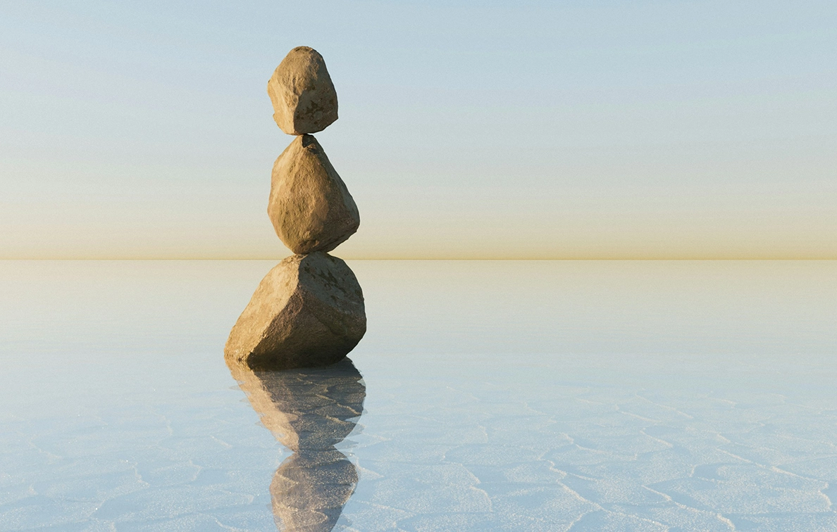Balanced stones on calm water — representing stability and generational continuity